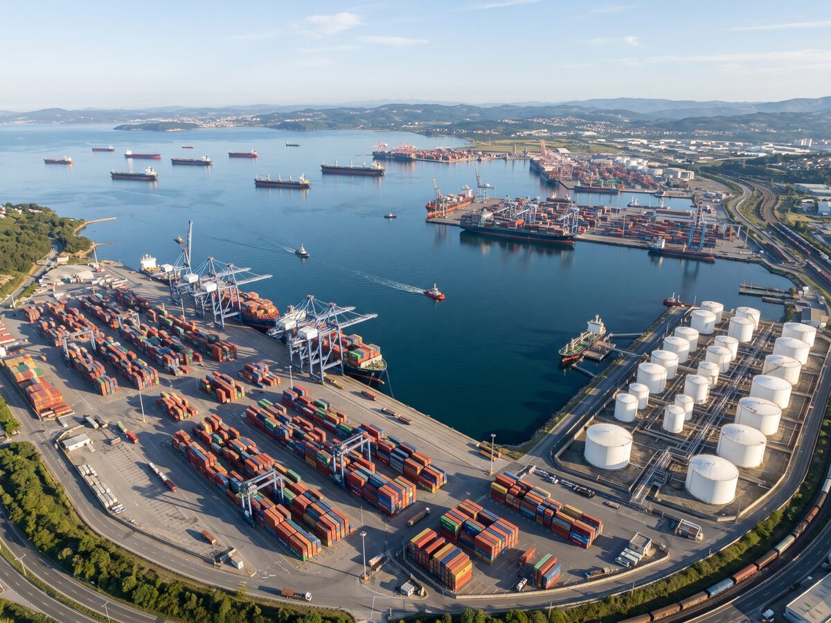 Vista aérea de porto organizado com navios, contêineres e tanques